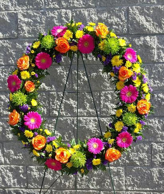 Customer wanted a very vibrant and colourful wreath. In the flower shop our florists used Ontario grown hot pink Gerbera, local purple statice, flat yellow chrysanthemums, green Revert mums and large bloomed Hig and Magic Roses. The wreath is 36 inches across.