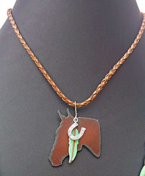Rustic Horse Head Necklace. On Adjustable Faux Leather Cord.
PROUDLY HANDMADE IN THE USA
This listing is for Horse Head necklace only.
Layers well with other necklaces.
Shown with 52" Turquoise Green Howlite necklace available on request-$60
Rustic Bronze Horse Head Pendant, with Verdigris Green Patina Feather and Silver Horseshoe Charms.
16.5"-18" long.
Other charms available on request. 
Pistol, Arrow, Dragonfly, Kokopelli available instead of the horseshoe.
