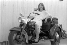 Emmylou Harris smiling pose in white lace top sitting on Harley