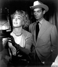 Barbara Stanwyck stares into lamp with unidentified actor or movie