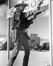 Clint Eastwood as Josey Wales in town by saloon firing two pistols 8x10 photo