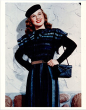 Deanna Durbin smiles as she poses with purse and hat against wall 8x10 photo