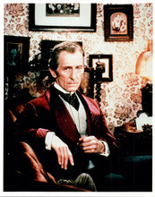 Peter Cushing looks suave in red jacket seated in chair 8x10 inch photo