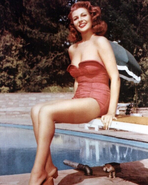 Rita Hayworth in strapless red swimsuit on diving board by pool