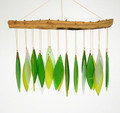 Wind chime presenting an array of stylized green leaves crafted of hand cut, sandblasted glass suspended from a natural driftwood canopy.