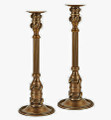 Pair of candle holders featuring fluted columns capped with castings accented with delicate leaves.  Crafted of brass with a rich antique brass finish.