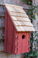 Brand new bird bunkhouse featuring a steep pitched roof. Crafted of wood and accented with a cypress-shingled roof. front opening for easy cleaning.  hand painted in a redwood hue with light distressing.