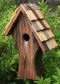 Brand new bird house featuring a curving asymmetrical design and bark-like rustic scored exterior. Hand crafted of solid cypress wood featuring a multi-hued hand-shingled roof accented with copper trim. 