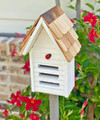 Brand new white ladybug house hand crafted of solid wood with a shingled roof accented with a metal peak that will age and weather beautifully through the years.  The facade features three horizontal entryways/exits and a decorative ladybug applique.