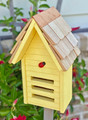 Brand new yellow ladybug house hand crafted of solid wood with a shingled roof accented with a metal peak that will age and weather beautifully through the years.  The facade features three horizontal entryways/exits and a decorative ladybug applique.