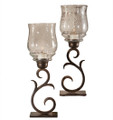 Pair of curvaceous scroll hurricane candle holders.  Cast of iron with a rich antique bronze finish, crowned with decorative glass hurricane shades.  