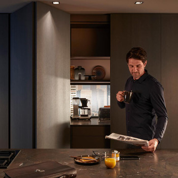 A sleek modern kitchen featuring the Blum REVEGO Duo system, with minimalist double pocket doors seamlessly concealing a stylish coffee station.